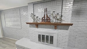 Een open haard met een metselwerk achterwand, een houten plank en decoratieve objecten.