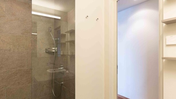 Une salle de bain moderne avec une douche à parois de verre, des toilettes et un plancher en bois.