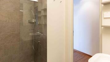 A modern bathroom with a glass-enclosed shower, a toilet, and a wooden floor.