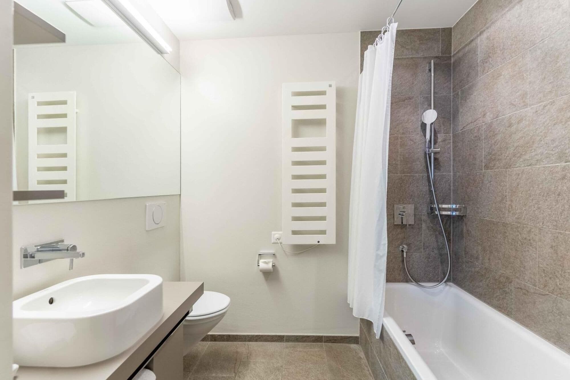 Un baño moderno con lavamanos, inodoro y zona de ducha.