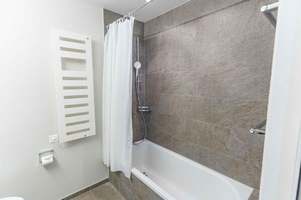 A bathroom with a shower, a toilet, and a towel rack.
