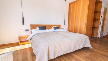 A modern bedroom with a wooden bed, a nightstand, and a wardrobe.
