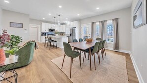 Una cocina moderna con armarios blancos, una isla central e iluminación colgante.