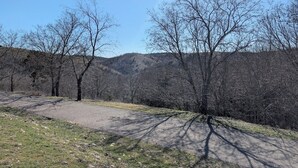 A clear sky with a sunbeam, a gravel path, and leafless trees in a hilly landscape. - The Most Beautiful Views in Turner Falls (Davis)