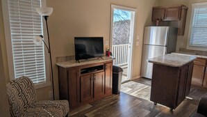 Eine moderne Küche mit Holzausstattung, einer eingebauten Kücheninsel, einem Kühlschrank und einem Fernseher auf der Arbeitsfläche.