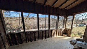 A rustic wooden room with large windows, a concrete floor, and a wooden bench.