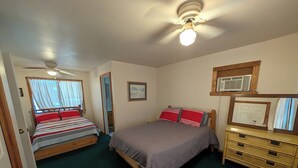 A bedroom with two beds, a ceiling fan, a dresser, and a window with curtains. - Mountain View 2 Bed Cabin (Davis)