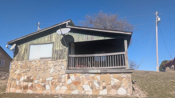 A small stone house with a wooden porch and a satellite dish. - Mountain View 2 Bed Cabin (Davis)