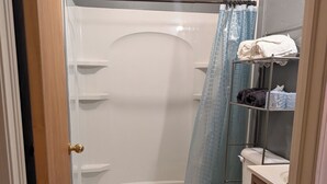 A bathroom with a bathtub, toilet, and a shower curtain. - Mountain View 2 Bed Cabin (Davis)