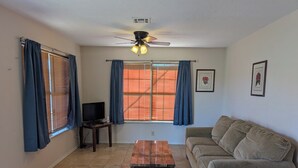A living room with a sofa, a coffee table, a TV, and a ceiling fan. - Mountain View 2 Bed Cabin (Davis)