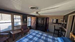 A bedroom with a large bed, a ceiling fan, a wooden door, a small table, and a chair. - The Most Beautiful Views in Turner Falls (Davis)