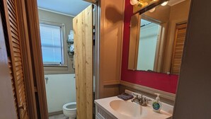A bathroom with a white sink, a mirror with lights, and a wooden door leading to another room. - The Most Beautiful Views in Turner Falls (Davis)