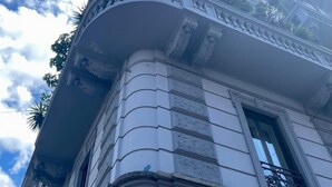 Un bâtiment doté d’un balcon incurvé, de détails architecturaux élaborés et surplombant un ciel dégagé parsemé de nuages.