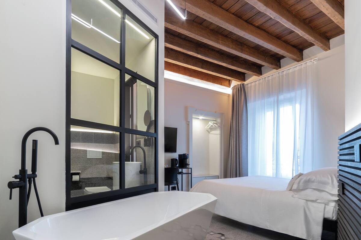 Une salle de bain moderne avec une baignoire sur pieds, un grand miroir et un espace douche.