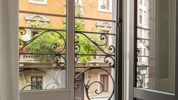 Une vue à travers une grille en métal, avec un bâtiment en briques et des balcons en arrière-plan.
