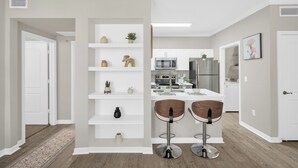 A modern kitchen with white cabinetry, a microwave, and a refrigerator. - 1BR Near Lake Conroe Pool, Gym & Parking (Magnolia)