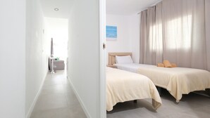Et hotelværelse med to senge, et lille skrivebord og en stol.