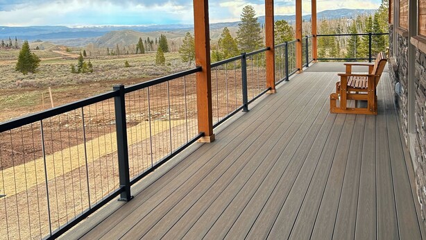 Una terraza de madera con un banco y barandilla que da a un paisaje montañoso.