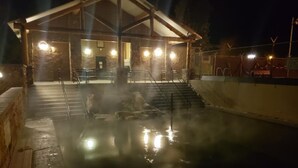 Un área de aguas termales con una estructura de madera y escalones que bajan al agua.