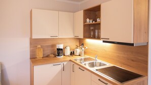 Een moderne keuken met houten kastjes, een RVS spoelbak en een koffiezetapparaat.