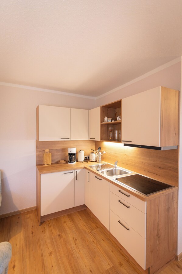 A modern kitchen with wooden cabinets, a stainless steel sink, and a coffee maker.