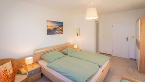 Een slaapkamer met een bed, nachtkastjes, een lamp, een schilderij aan de muur en een garderobe.