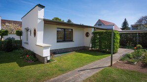 Een wit huis met een rood dak, een kleine tuin en een pad naar de ingang.