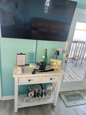 A room with a television mounted on the wall, a desk with a computer, books, and a pair of binoculars. - MANATEE COTTAGE:  Gulf Front 2-bedroom house (Hudson)