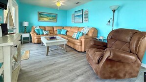 A living room with a brown leather sofa, a glass coffee table, and a brown leather armchair. - MANATEE COTTAGE:  Gulf Front 2-bedroom house (Hudson)