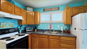 A kitchen with wooden cabinets, a white stove, a sink, and a refrigerator. - MANATEE COTTAGE:  Gulf Front 2-bedroom house (Hudson)