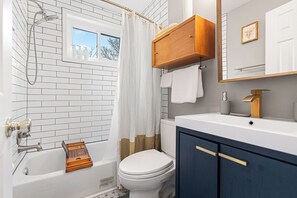 Une salle de bain avec une baignoire blanche, des toilettes et un meuble-lavabo avec un miroir.