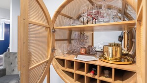 Un porte-bouteilles en bois doté de plusieurs étagères, une bouteille de vin et des verres.