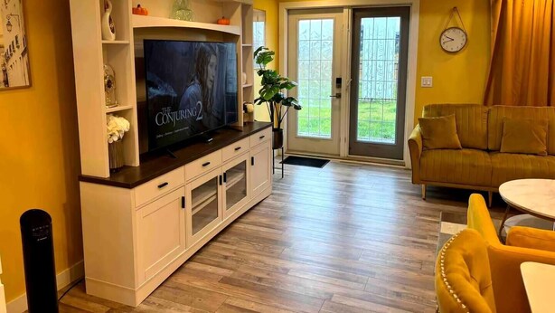 A living room with a flat-screen TV, a sofa, a dining table, and a plant. - HOME AWAY FROM HOME (Winnipeg)