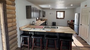 Une cuisine moderne dotée d’un grand îlot central, de tabourets de bar et d’un four encastré.