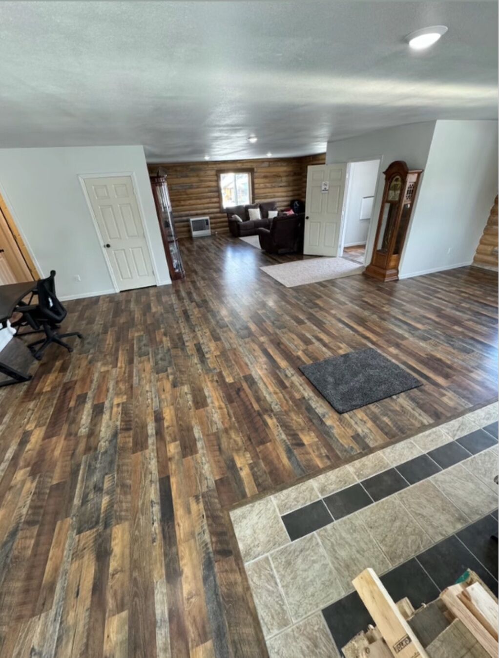 A spacious room with a wooden floor, a large window, and a fireplace.