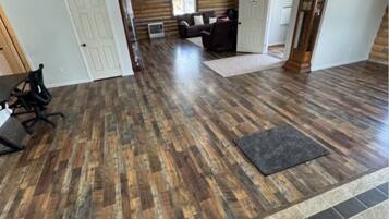 A spacious room with a wooden floor, a large window, and a fireplace.