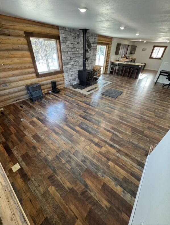 A spacious living area with a stone wall, a fireplace, and a kitchen area with a bar.