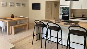 Une cuisine moderne dotée d’un îlot central, de tabourets de bar et d’une table à manger avec des chaises.