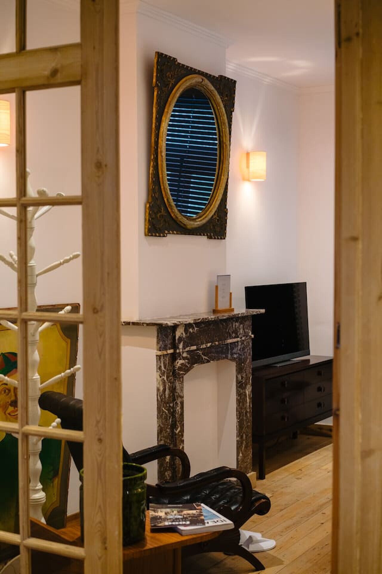 A room with a wooden staircase, a fireplace, a television, and a framed mirror on the wall.