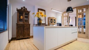 A modern kitchen with a wooden cabinet, a white island, and a vase with flowers. - Circa 1929 - Suite met keuken (Ostend)