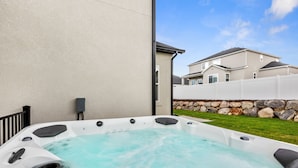 Een bubbelbad met een stenen muur en een huis op de achtergrond.