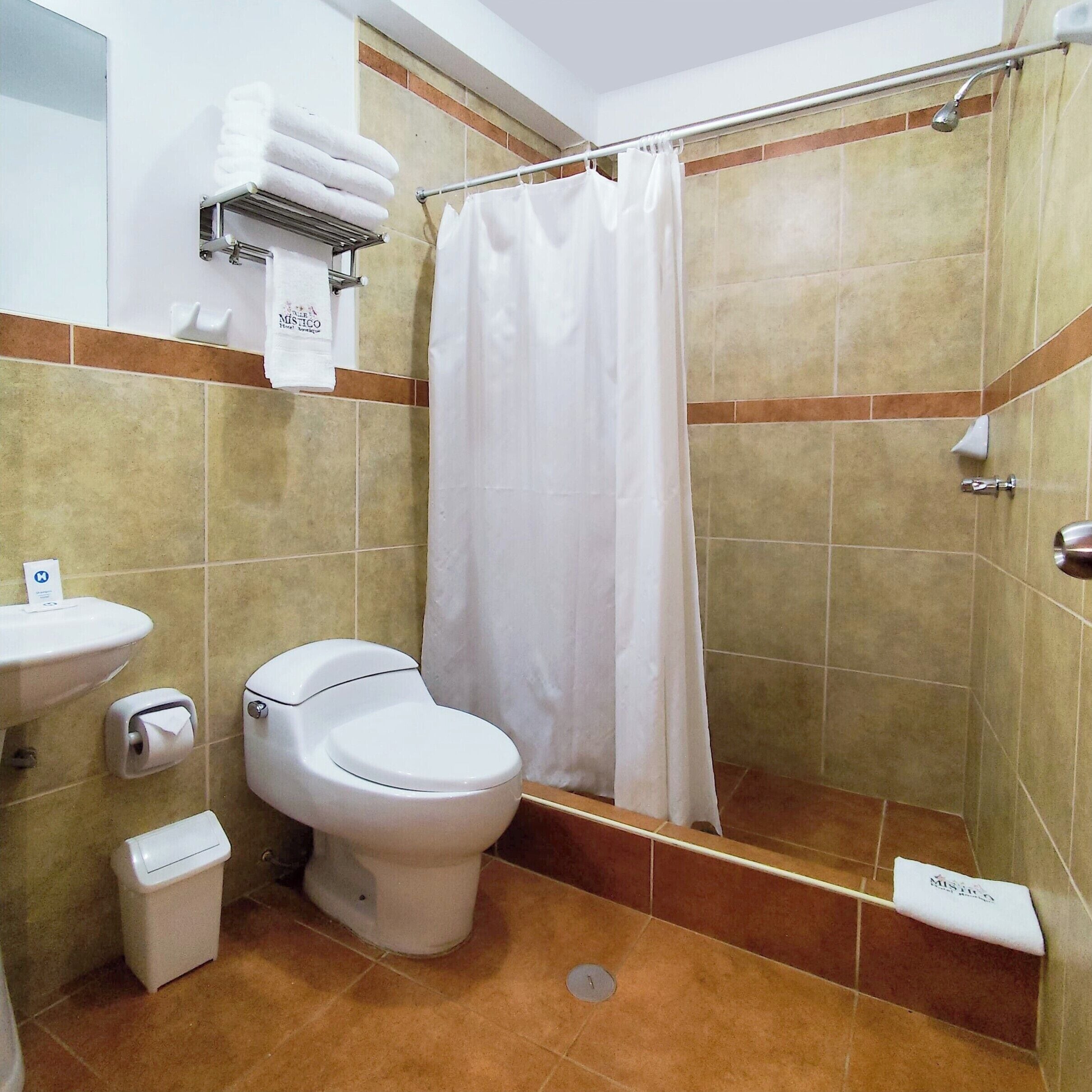 A bathroom with a toilet, sink, and shower curtain.