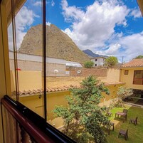 Vista de un patio con una montaña al fondo, una piscina pequeña y mobiliario exterior.