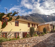 Un edificio tradicional con paredes de piedra, ventanas rojas y una escalera de piedra que conduce a una puerta.
