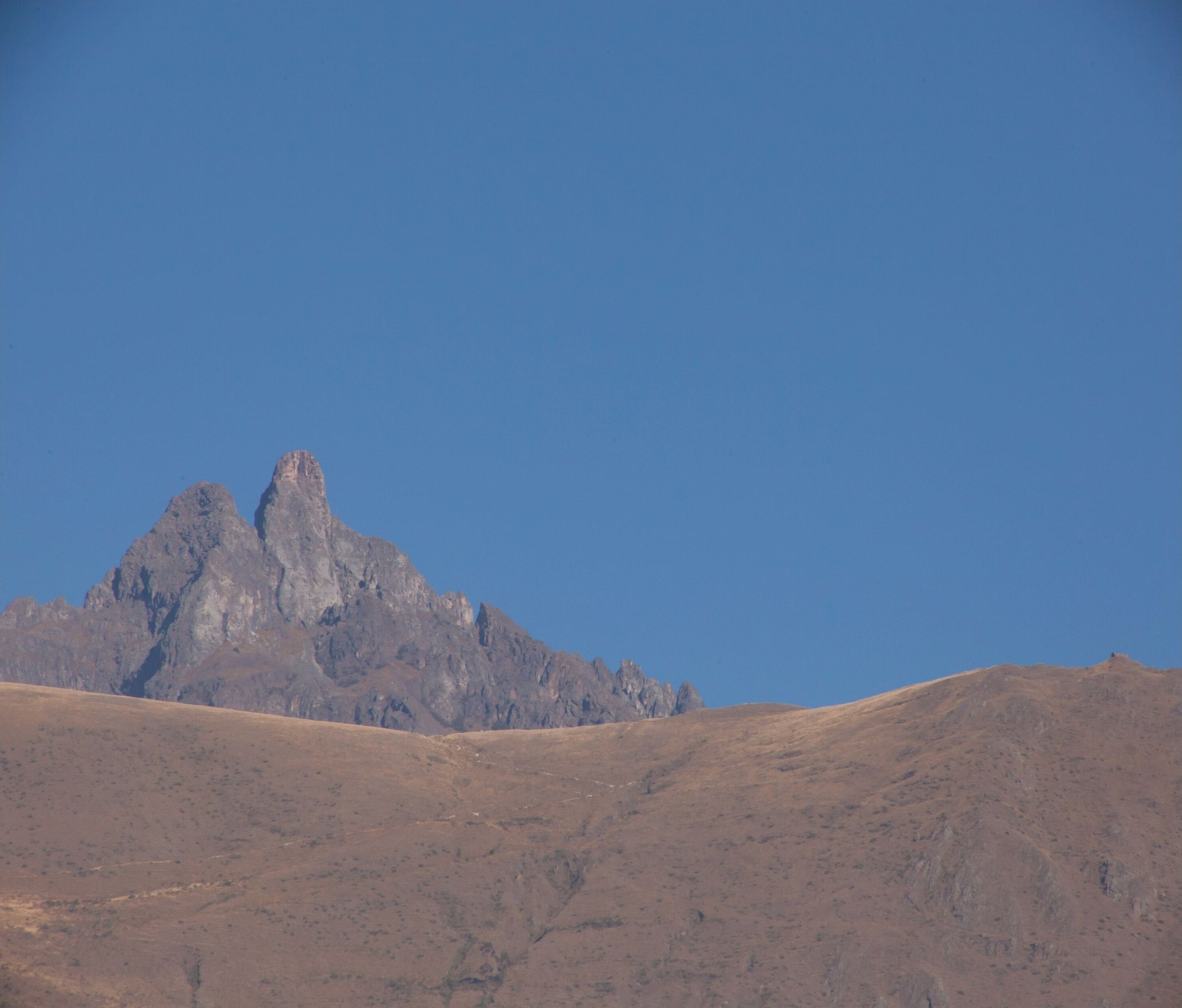 A mountain landscape with a prominent peak and a flat, barren foreground.