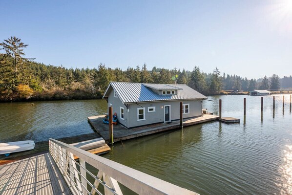 A houseboat docked at a pier with a dock and a small boat nearby.