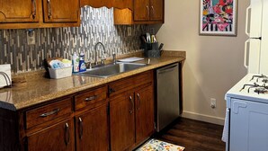 Una cocina con armarios de madera, un lavamanos de acero inoxidable y un refrigerador blanco.