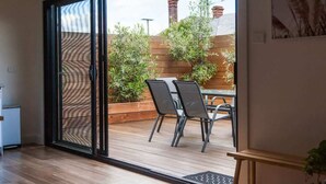 A room with a sliding glass door leading to an outdoor patio with a table and chairs. - Renovated Character Home (Invermay)