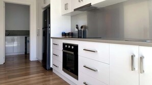 A modern kitchen with white cabinetry, stainless steel appliances, and a wooden floor. - Renovated Character Home (Invermay)