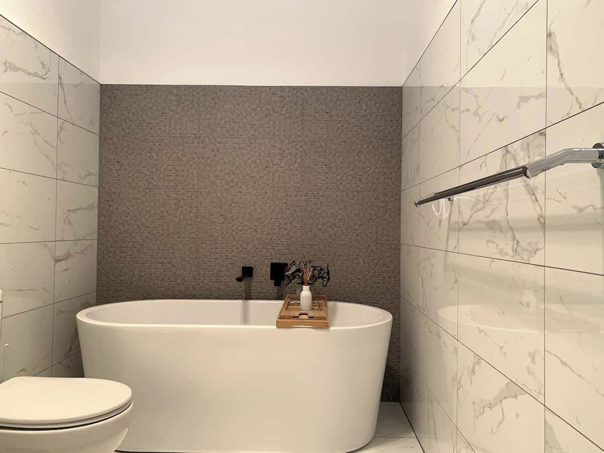 A modern bathroom with a freestanding bathtub, a toilet, and a towel rack.